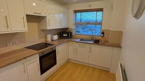 A compact kitchen with white cabinets, a microwave, a toaster, and a window with blinds. - 2 Bed-sleeps 3-parking-town Centre (Northallerton)