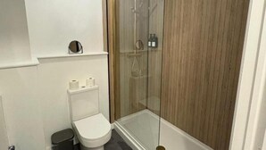 A modern bathroom with a glass-enclosed shower, a toilet, and a small shelf with toiletries. - 2 Bed-sleeps 3-parking-town Centre (Northallerton)