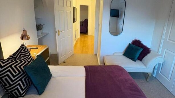 A bedroom with a bed, a desk, a chair, a sofa, and a door leading to another room. - 2 Bed-sleeps 3-parking-town Centre (Northallerton)