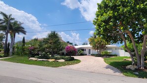 A residential property with a paved driveway, palm trees, and a well-maintained lawn. - Charming waterfront house with 3-bedrooms, 3-full bathrooms and pool (Pompano Beach)
