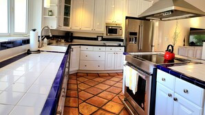 A modern kitchen with white cabinets, a stainless steel refrigerator, a microwave, and a red kettle on the counter. - Charming waterfront house with 3-bedrooms, 3-full bathrooms and pool (Pompano Beach)
