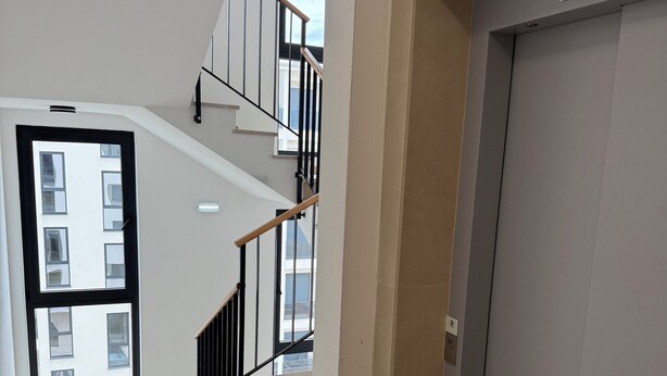 A modern interior with a staircase, a door, and a view of the outside.