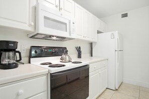 Una cocina moderna con armarios blancos, estufa, microondas y refrigerador.