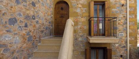 Un bâtiment en pierre avec une porte en bois et un balcon.