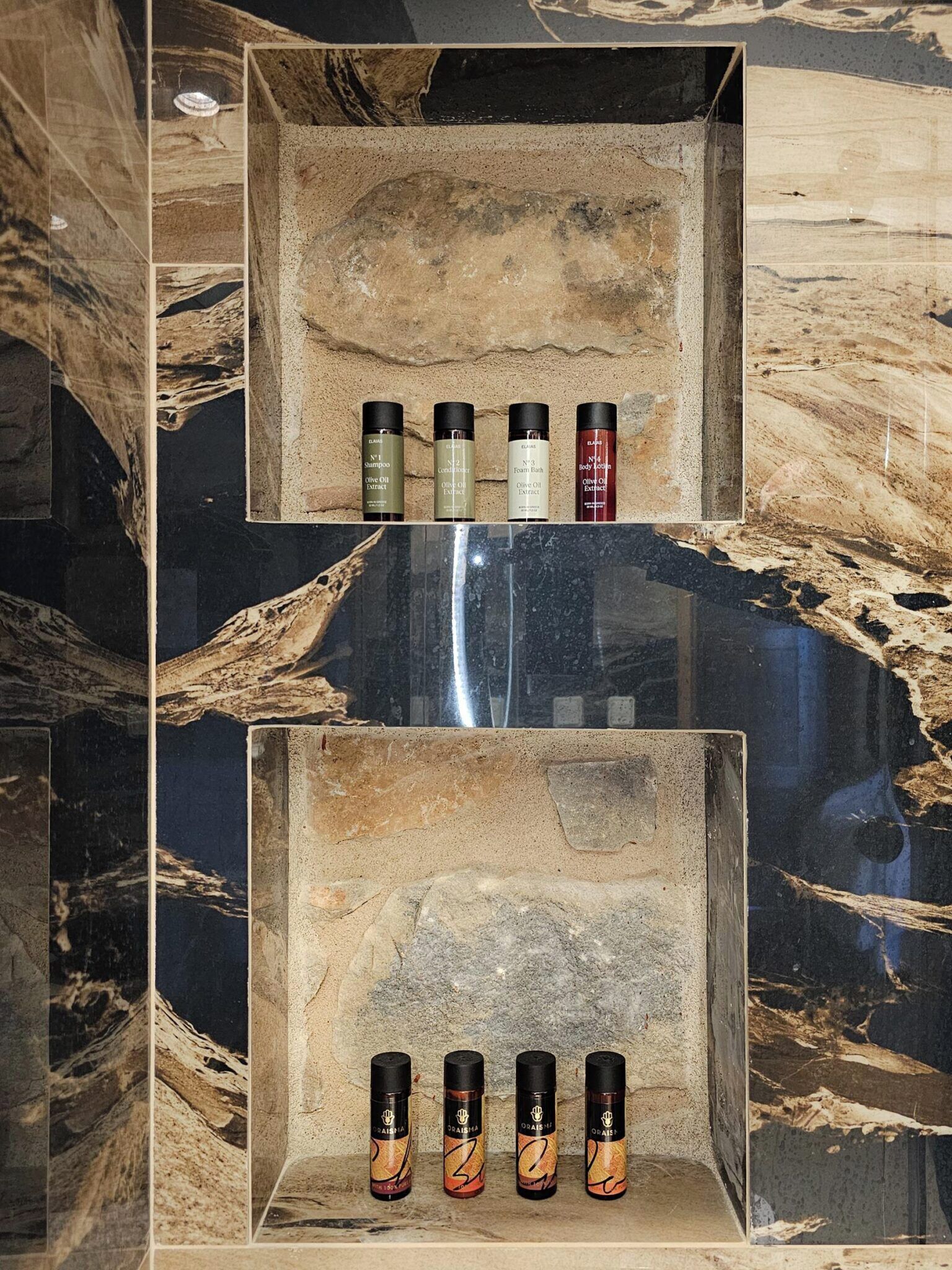 A marble wall with shelves holding various toiletries.