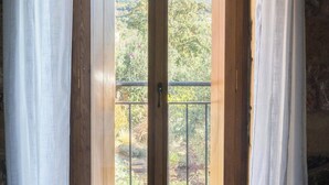 A wooden door with a glass panel, white curtains, and a view of a mountainous landscape.