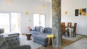 A modern living room with a sectional sofa, a round coffee table, and a dining area with a wooden table and chairs. - Twilight Palace (Luxor)