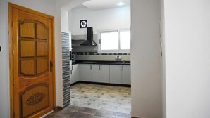 A kitchen with white cabinets, a black range hood, and a window. - Twilight Palace (Luxor)