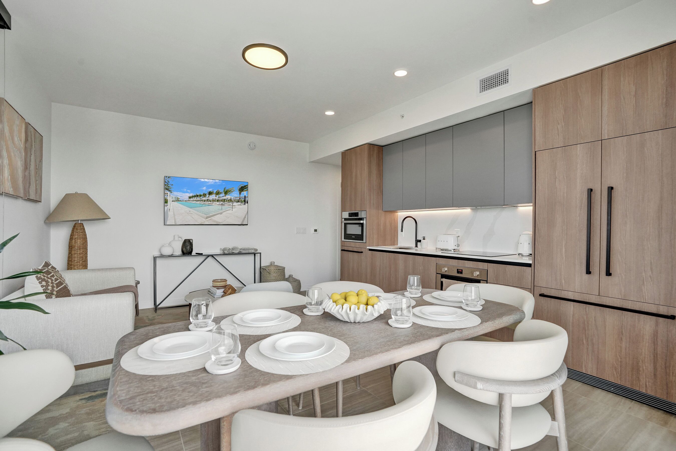 A modern kitchen with wooden cabinets, a dining table set for four, and a painting on the wall.