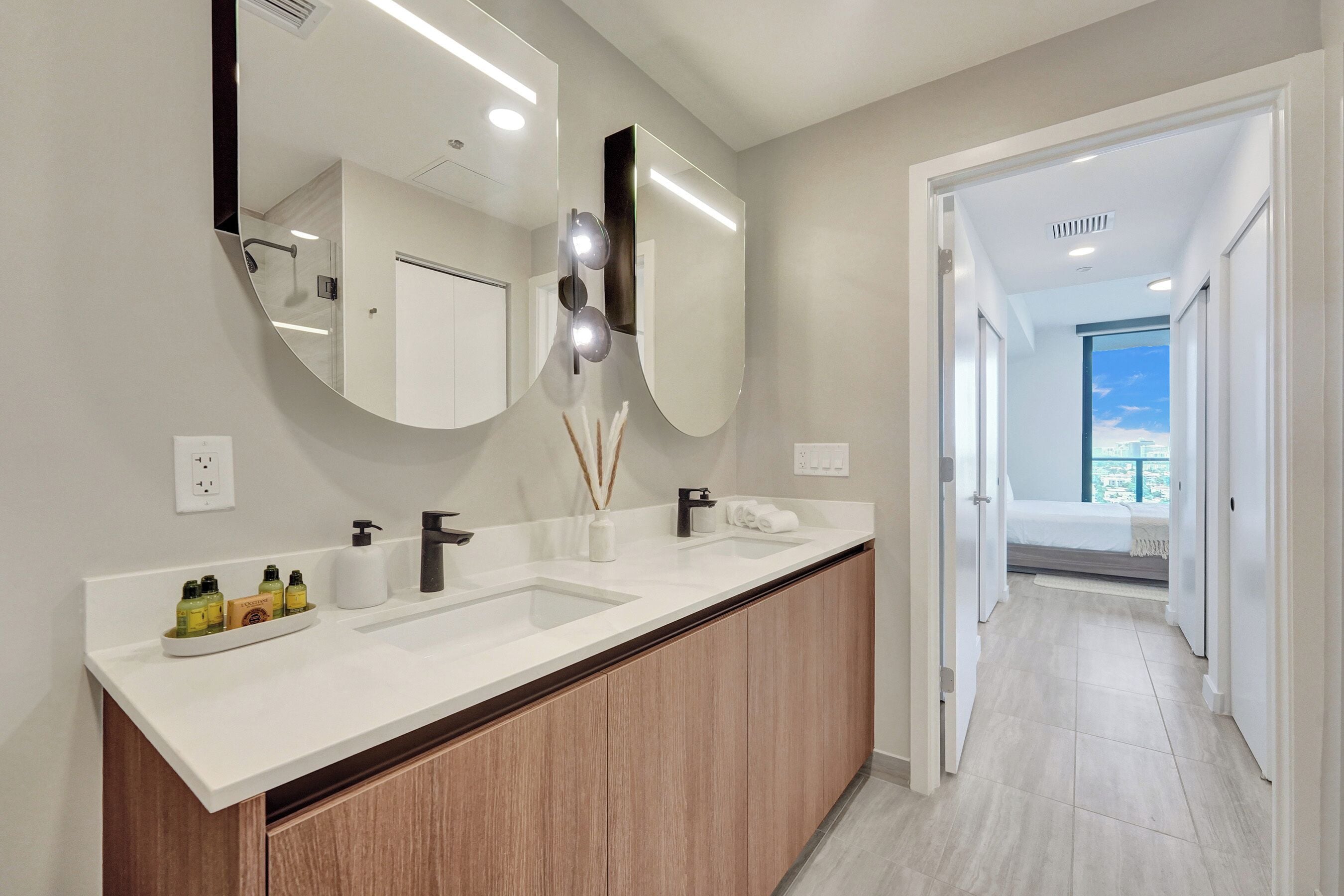Un baño moderno con un espejo grande, dos lavamanos y un mueble de tocador con armarios de madera.