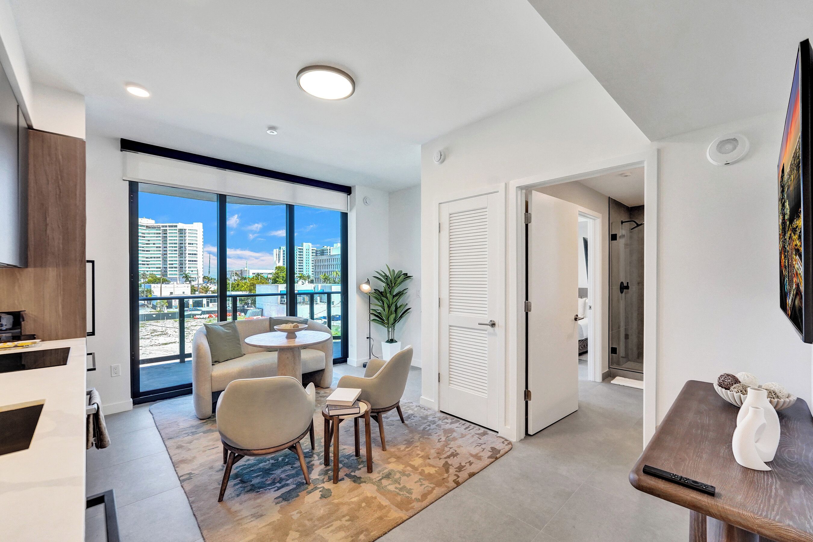 A modern living room with a large window, a round table, and a sofa.