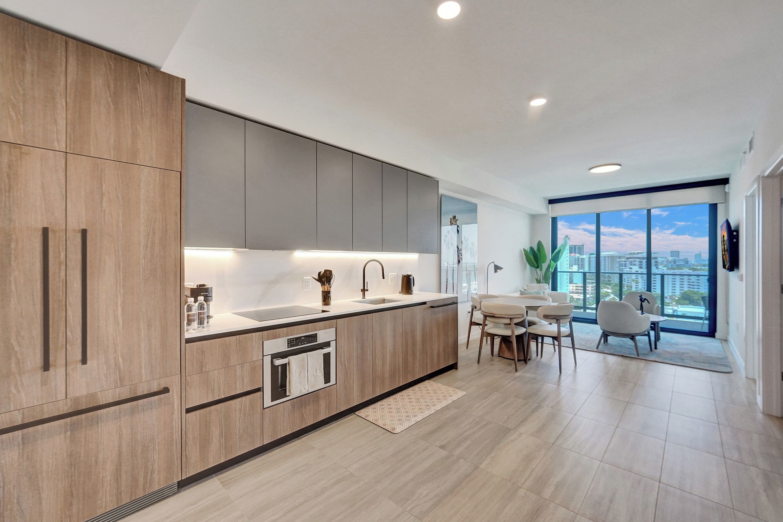 A modern kitchen with a large island, built-in appliances, and a dining area with a view of the city.