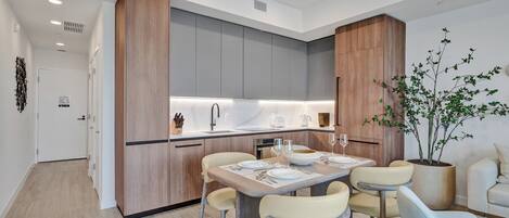 Una cocina moderna con armarios grises, una pared decorativa de madera y un comedor con mesa lista para cuatro.