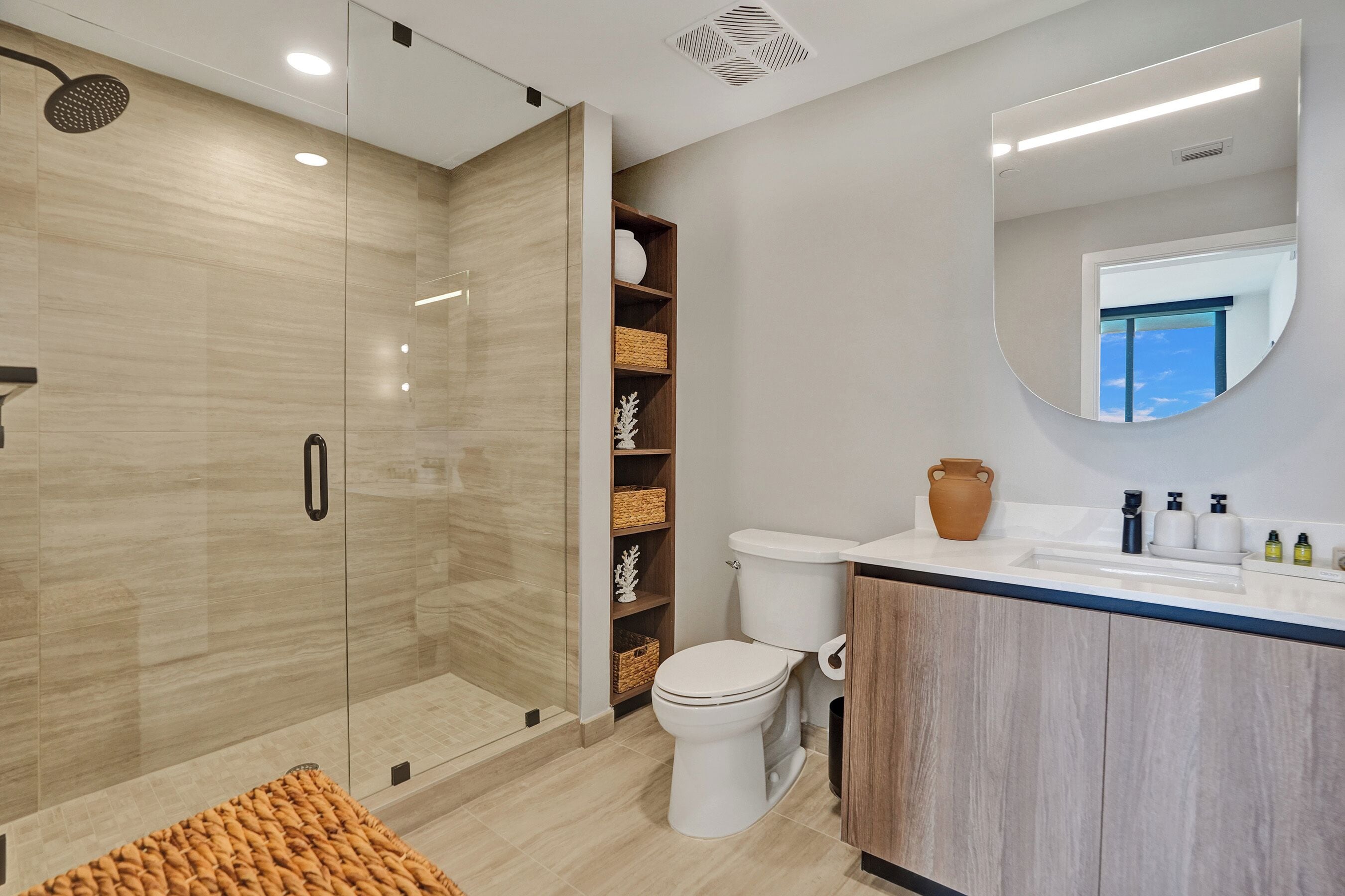 A modern bathroom with a glass-enclosed shower, a toilet, and a vanity with a mirror.