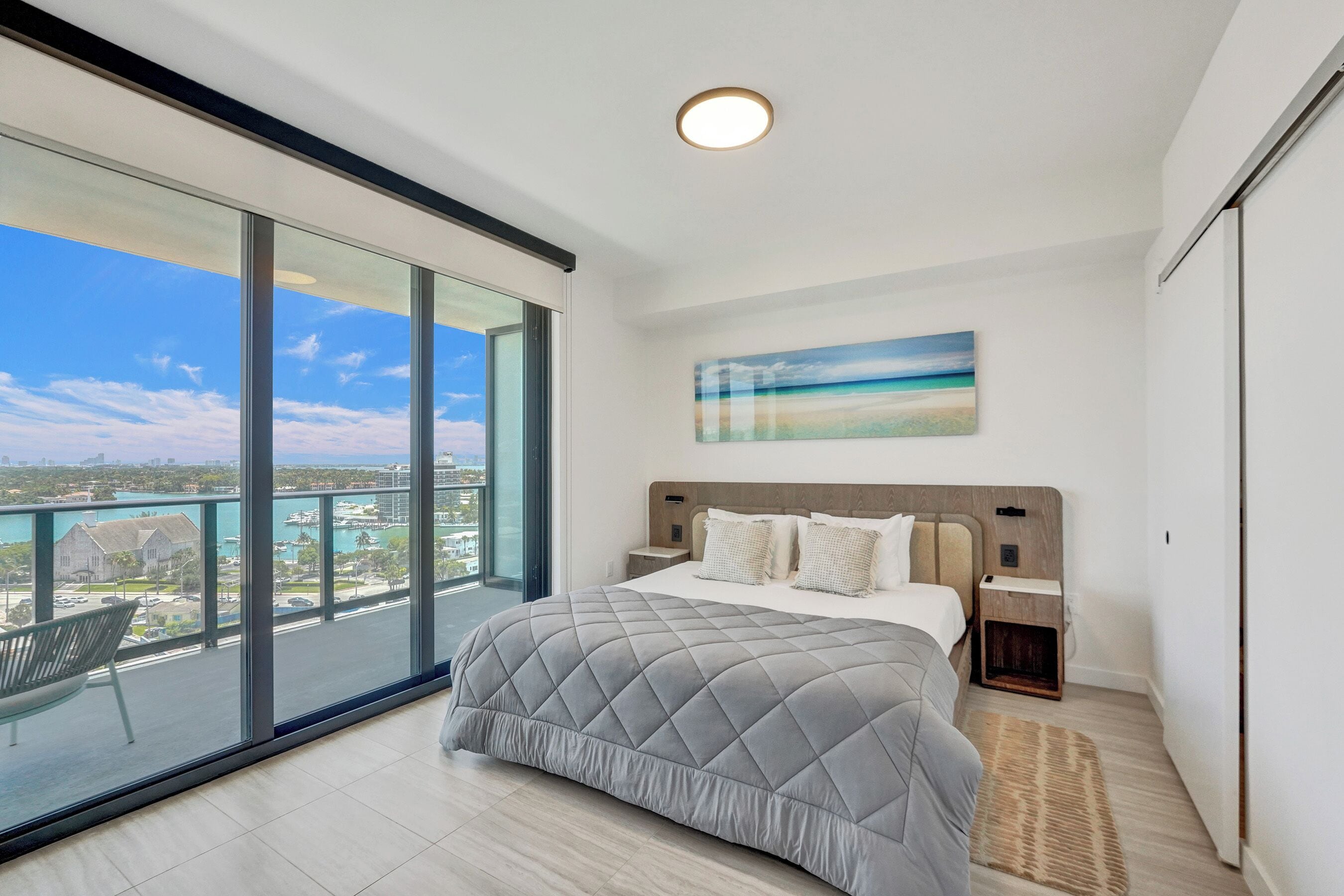 A modern bedroom with a large bed, a view of the city, and a balcony.