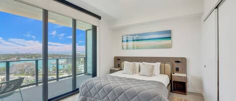 A modern bedroom with a large bed, a view of the city, and a balcony.