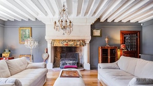 A living room with two sofas, a fireplace, and a chandelier.