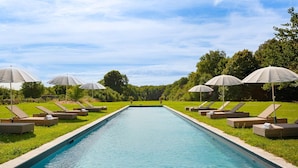 A rectangular pool with lounge chairs and umbrellas on either side.
