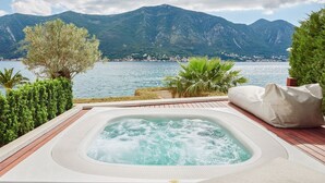 Un bain à remous sur une terrasse en bois, avec vue sur un lac et des montagnes.