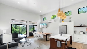 A modern kitchen with white cabinets, a wooden island, and a large window overlooking a garden. - Villa with Minimalist Design & Scenic Deck with Private Infinity Pool and Jungle Views (Coco)