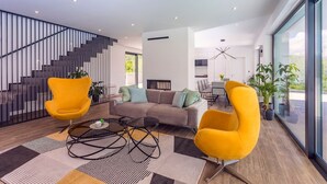 Ein modernes Wohnzimmer mit Treppe, einer Couch, zwei gelben Sesseln und einem Couchtisch.