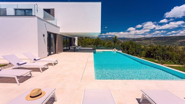 Ein moderner Poolbereich mit Liegestühlen und freiem Blick auf die Landschaft.