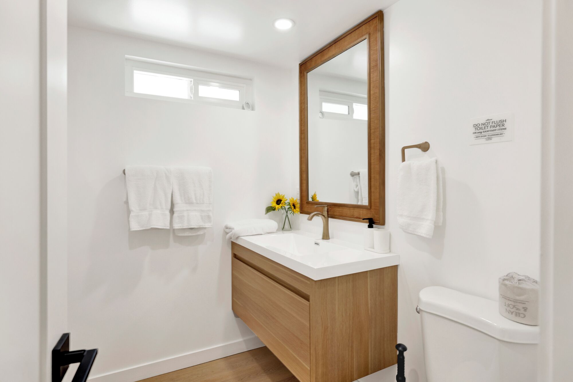 A modern bathroom with a wooden vanity, a large mirror, and a toilet.