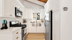 Una cocina moderna con armarios blancos, electrodomésticos de acero inoxidable y suelo de madera.
