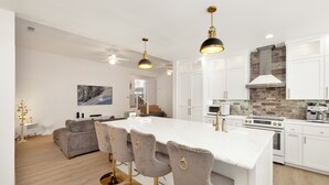 Een moderne keuken met witte kastjes, een marmeren eiland en een tegelwand.