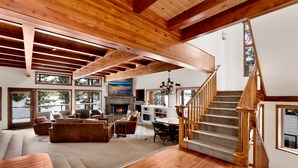 A spacious living area with a fireplace, wooden flooring, and a staircase. - Bear Lake Lodge #2547 (Big Bear Lake)