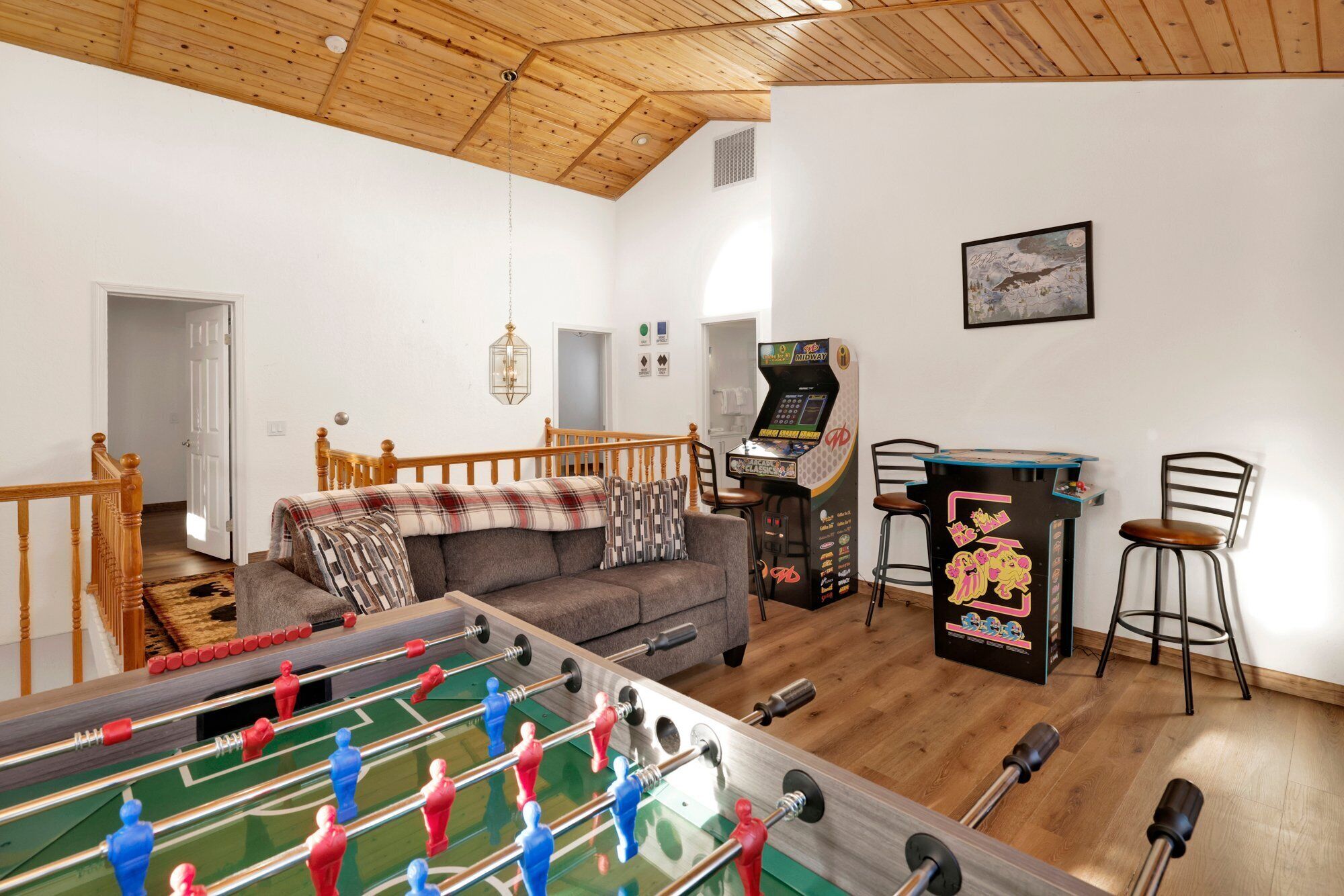 A cozy living room with a foosball table, a sofa, and a gaming console.