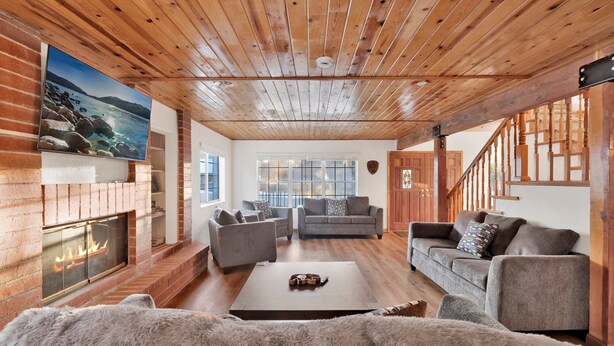 Una sala de estar acogedora con chimenea, techo de madera y un ventanal grande.