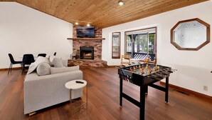 Una sala de estar con chimenea, un sofá, una mesa de fútbol de mesa y un ventanal con vistas.