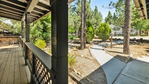 Un espacio al aire libre techado con cubierta de madera, rodeado de árboles y un cielo despejado.