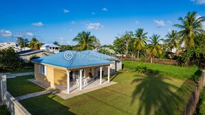A single-story house with a blue roof, a covered porch, and a well-maintained lawn. - Villa Perrin Évasion à 9 min de l'aéroport de la Guadeloupe (Les Abymes)