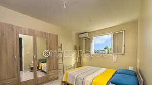A bedroom with a bed, wardrobe, and a window with a view. - Villa Perrin Évasion à 9 min de l'aéroport de la Guadeloupe (Les Abymes)