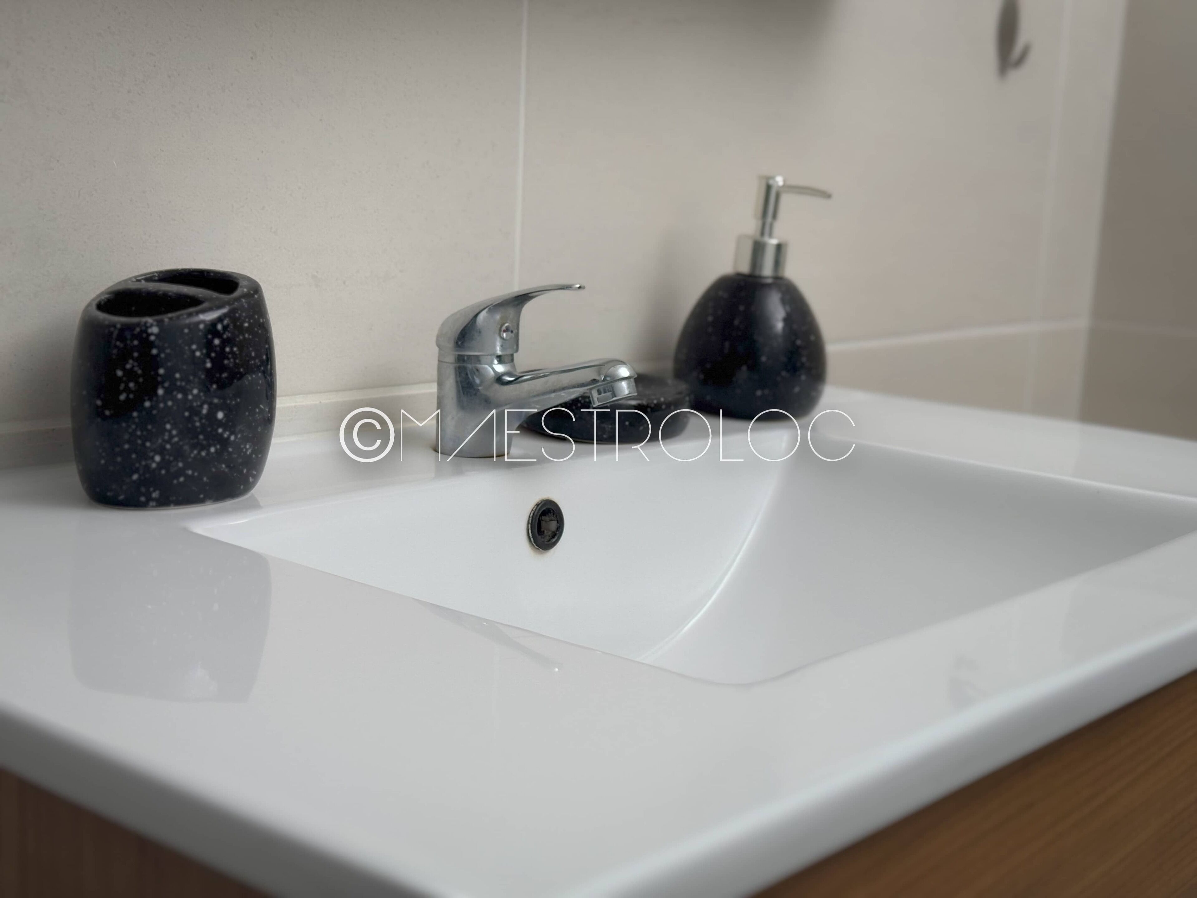 Een witte wastafel met een moderne kraan en een zeepdispenser.