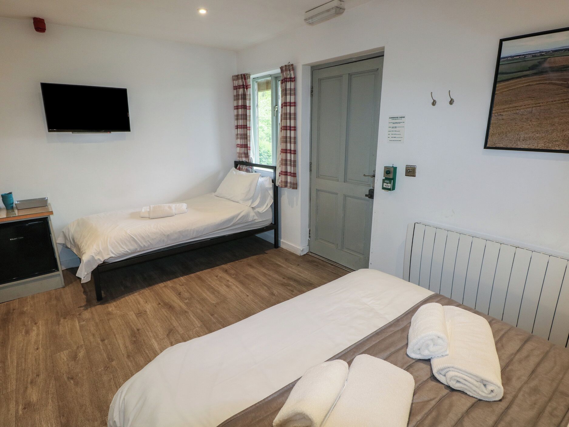 Un dormitorio con dos camas, televisión, puerta y radiador.