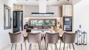 Une cuisine moderne dotée d’un îlot central, de tabourets de bar et offrant une vue sur l’extérieur.