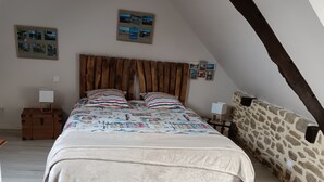 Un dormitorio con cama, maleta, mesita de noche y pared de piedra.