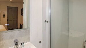 Un baño con lavamanos, espejo y cabina de ducha de vidrio.