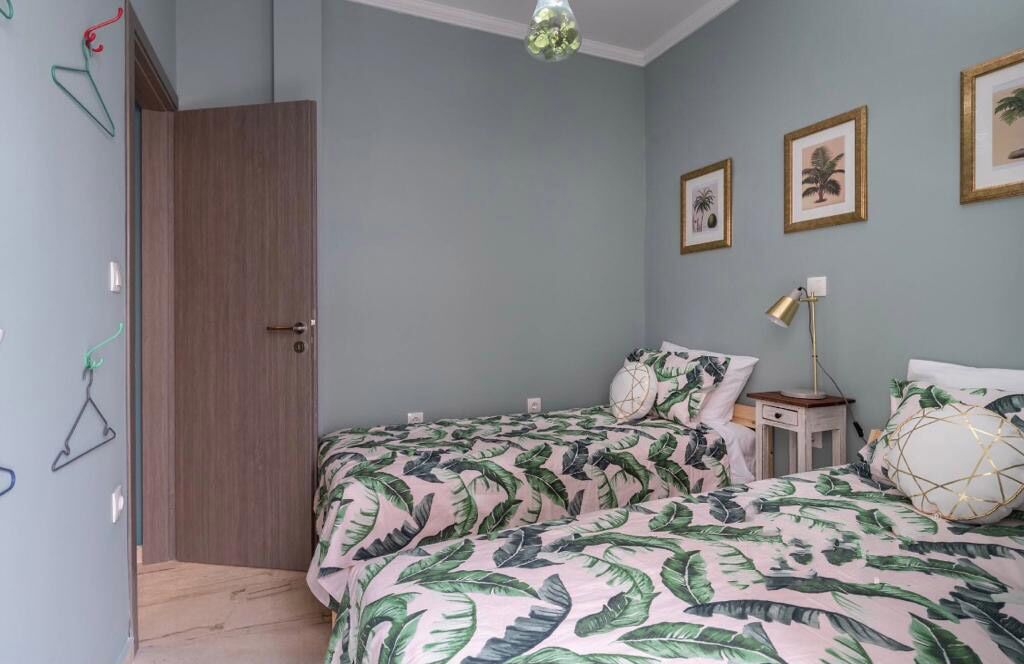 A bedroom with two beds, a wooden door, and wall-mounted clothes hangers.