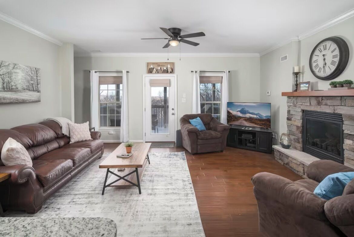 A living room with a brown leather couch, a wooden coffee table, and a fireplace.