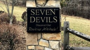 Une statue d’un ours portant un chapeau et un collier de fleurs, avec une pancarte sur laquelle on peut lire : « SEVEN DEVILS : découvrez notre attitude positive ! »