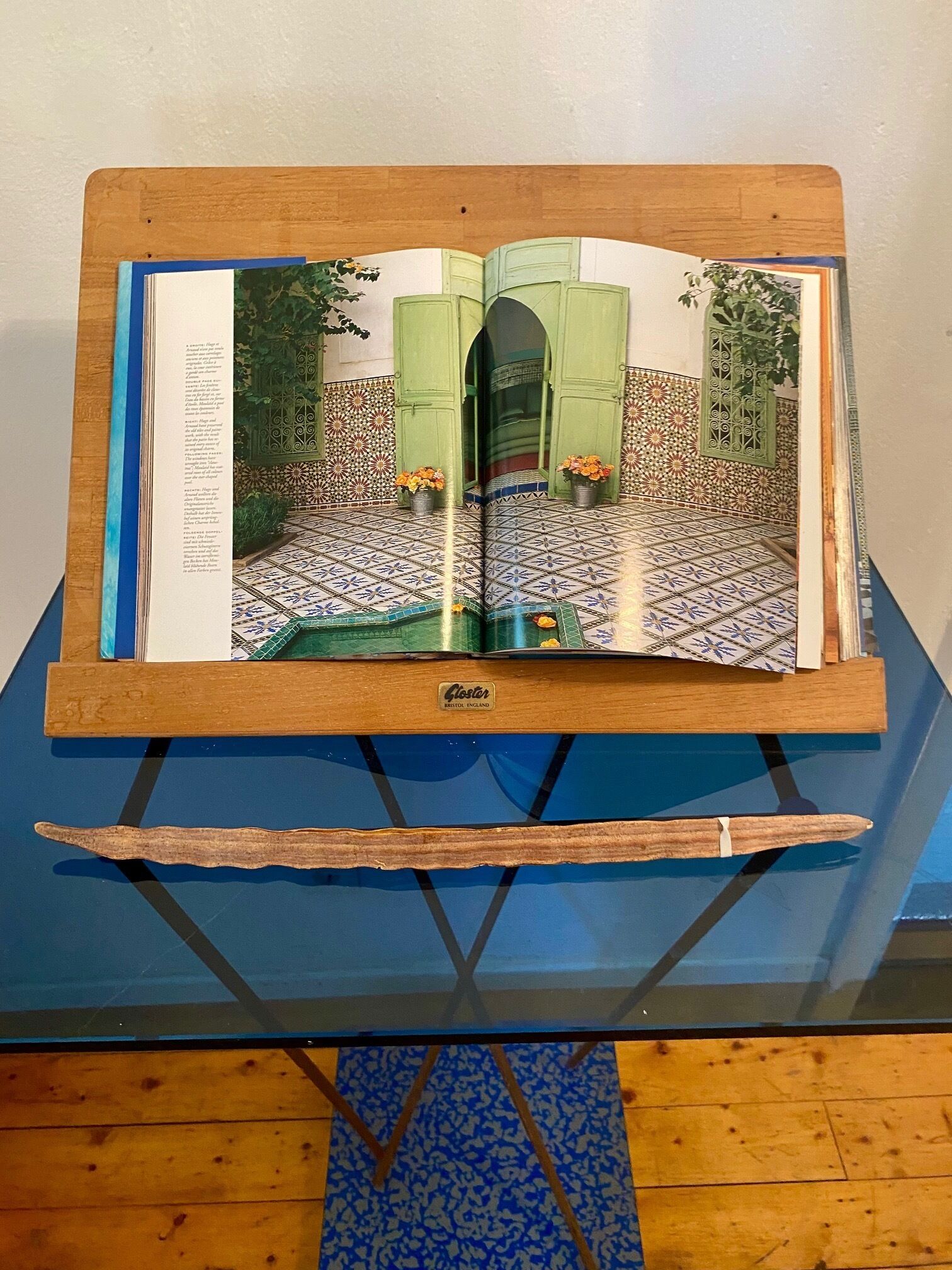 Ein offenes Magazin auf einem hölzernen Ständer, darunter ein blauer Tisch.