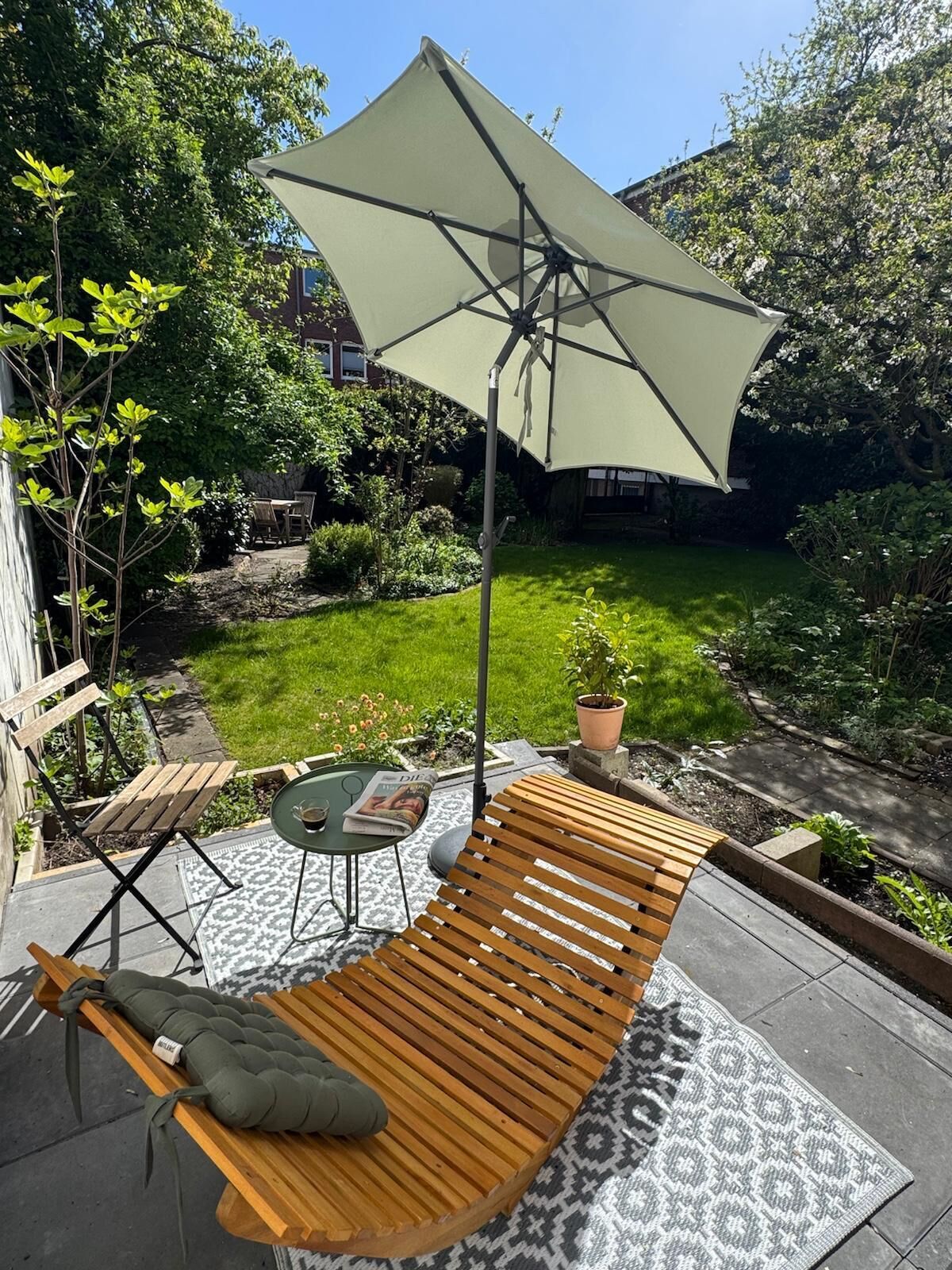 Une terrasse avec un banc en bois, une table et un parasol.