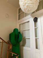 A staircase with a green textured object hanging on the wall, a white door with frosted glass panels, and a white textured ceiling light.
