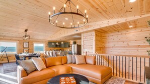 Un interior de cabaña acogedor, con un amplio sofá de cuero, un comedor y una cocina.