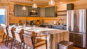 Una cocina moderna con paneles de madera, electrodomésticos de acero inoxidable y una isla de mármol con taburetes de bar.