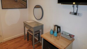 A room with a wooden desk, a small chair, a mirror, a kettle, and a TV mounted on the wall. - Chestnut (Cowbridge)